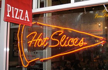 A red banner reading Pizza next to a neon sign with the words Fresh Hot Slices